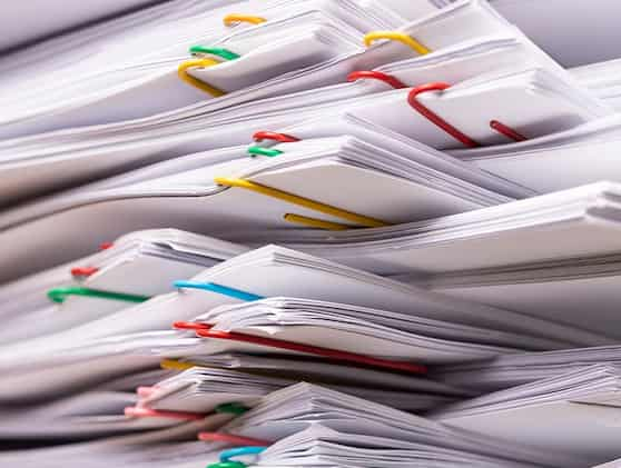 A stack of papers held together by yellow, green, red, blue, and pink paperclips, representing organization and work-related documents in a professional setting.